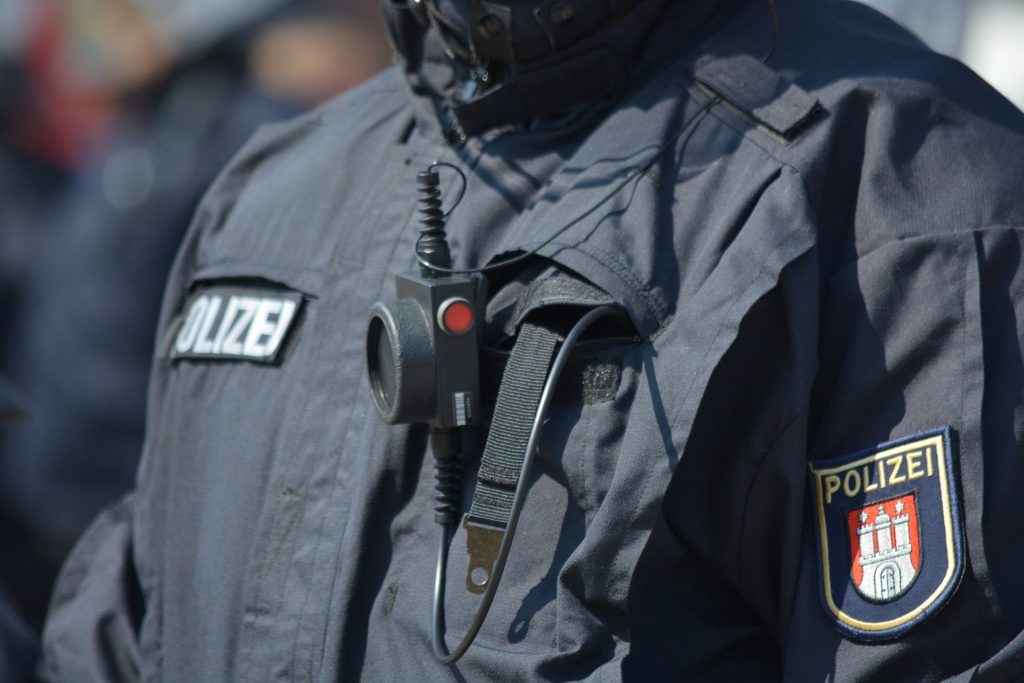 Bodycam an der Brusttasche eines Polizisten mit blauer Jacke